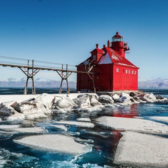 Icy lake with a lighthouse in the background.