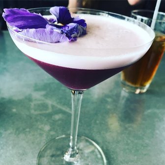 Closeup of a mixed drink cocktail with a violet garnish