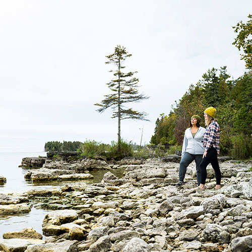 Two women standing on rocks looking out to the lake.