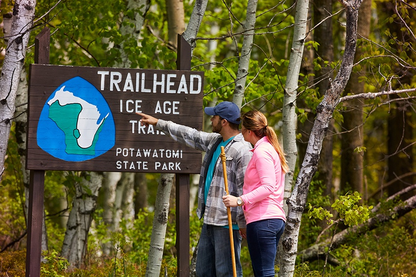 A man and a woman check out the Ice Age Trail trailhead sign at Potawatomi State Park