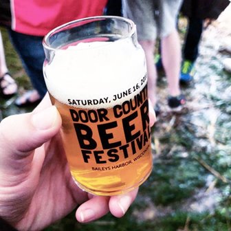 A hand holding a beer glass that says Door County Beer Festival.