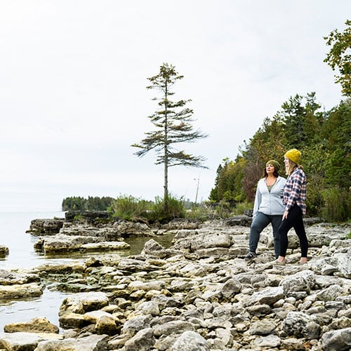 Baileys Harbor Two women standing on rocks looking out to the lake.
