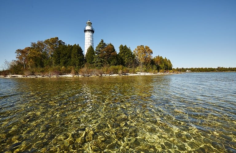 Lighthouses A white lighthouse surrounded by trees at the lakefront.