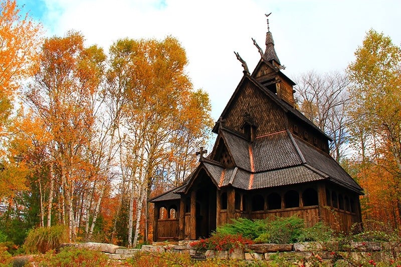 Weddings Wooden building in a clearing surrounded by trees with fall colors.