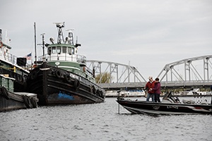 Two people fishing off a boat in a marina