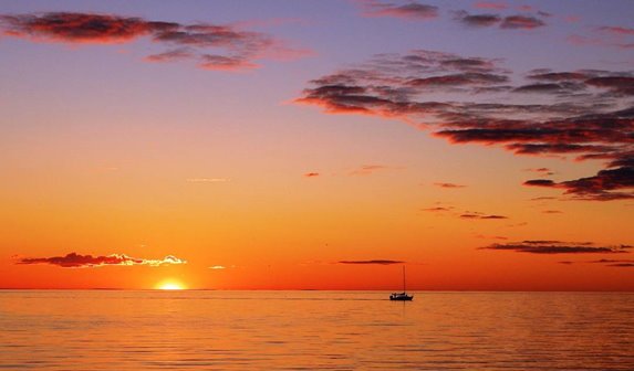 A lone sailboat on the lake at sunrise