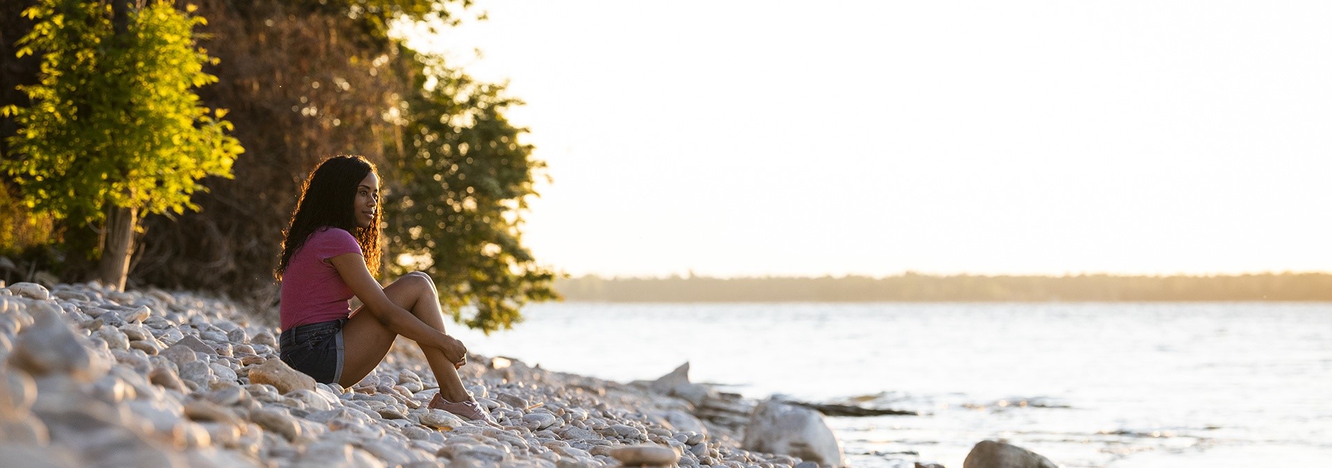 Person sitting enjoying the sunset lakeside.