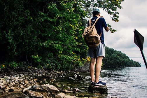 A hiker standing on a rock at the edge of the lake.