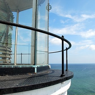 Closeup of a lighthouse light overlooking the lake.