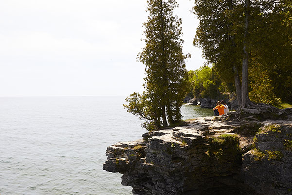 Two people sitting looking out over a cliff